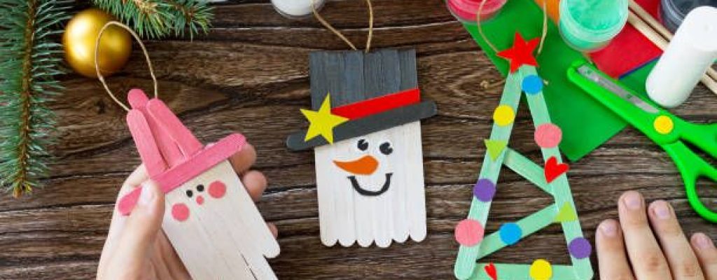 A child is holding Christmas decoration or Christmas gift wooden sticks. Handmade. Project of children's creativity, handicrafts, crafts for kids.